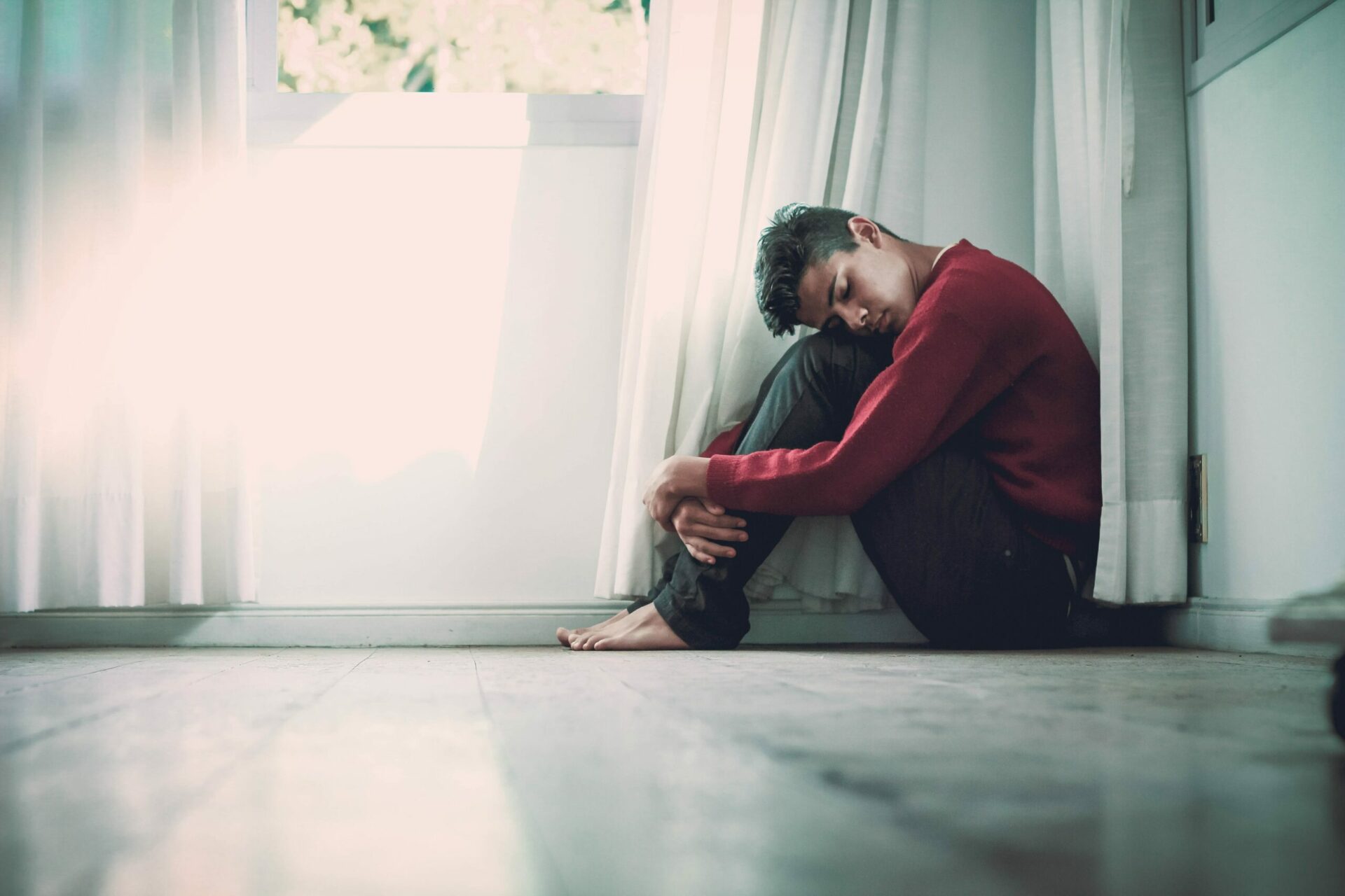 man alone sitting on the floor in the corner